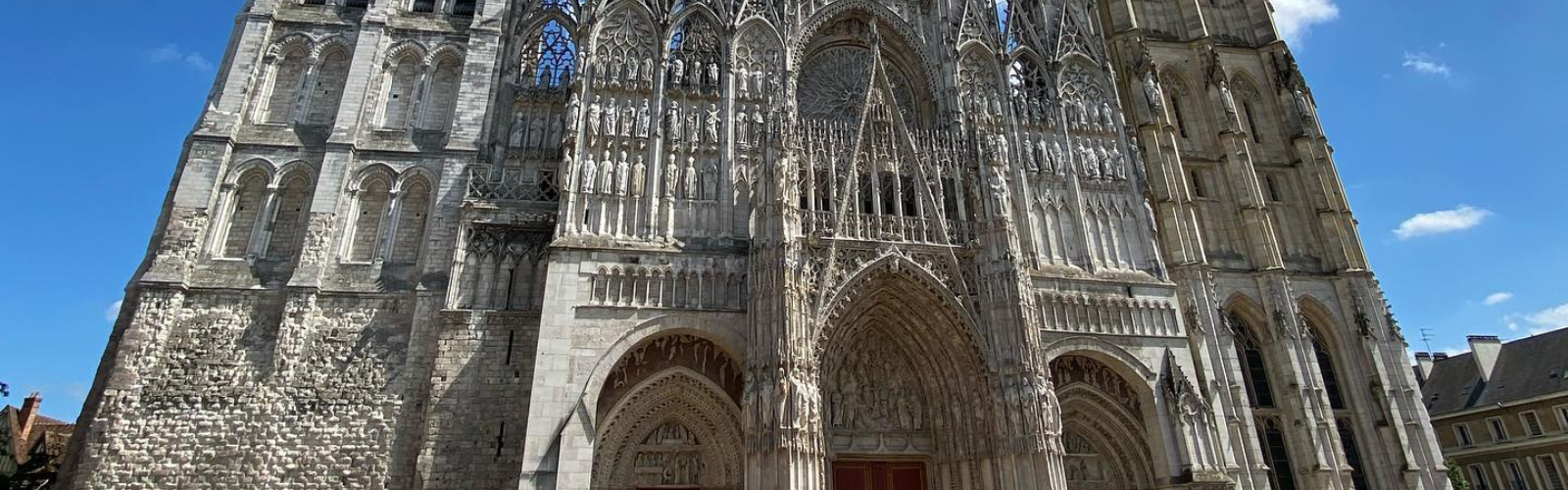 Exterior of the Notre Dame cahedral in Rouen. The architecture is gothic, making the building both mundane and detailed. archways scale the cathedral as well.